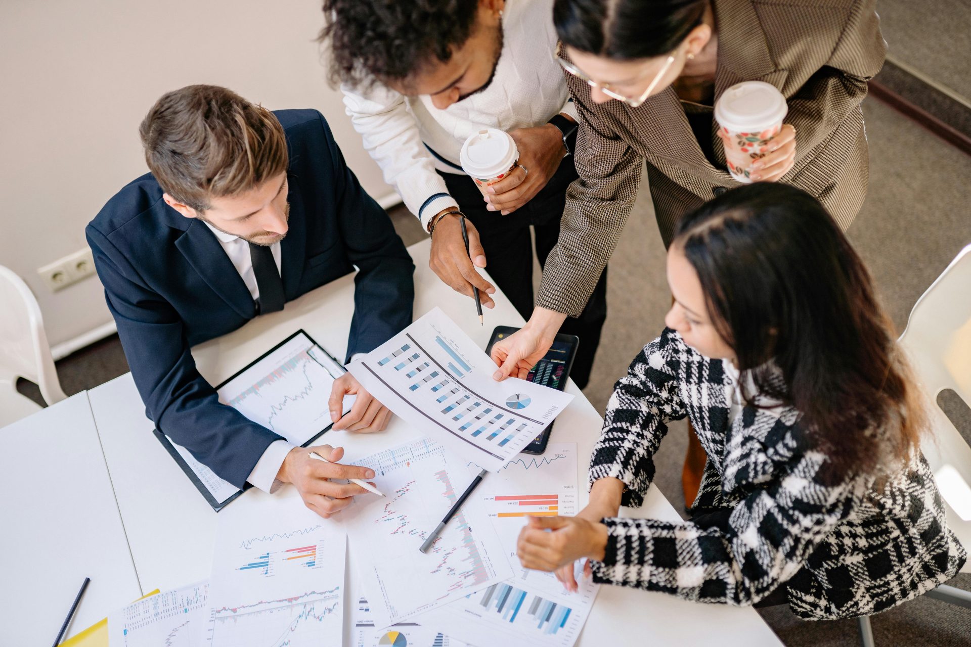 A diverse team in business attire collaborates over graphs and charts for a successful project.