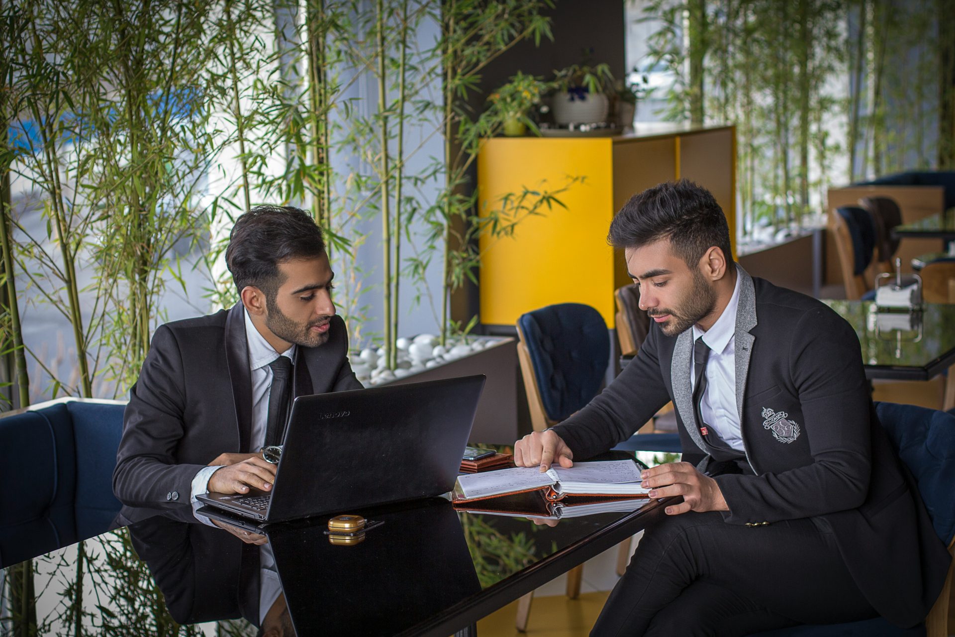 man in black suit jacket sitting beside man in black suit