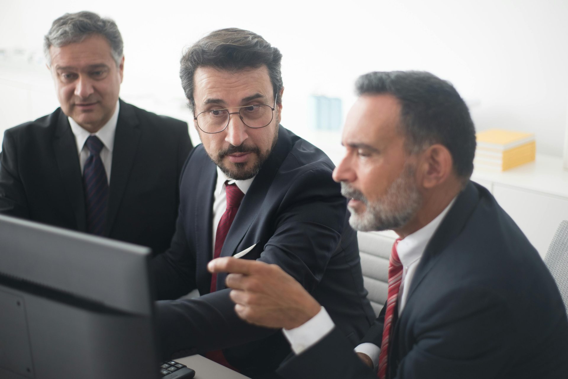 Three men in a corporate meeting discussing a project in a modern office.