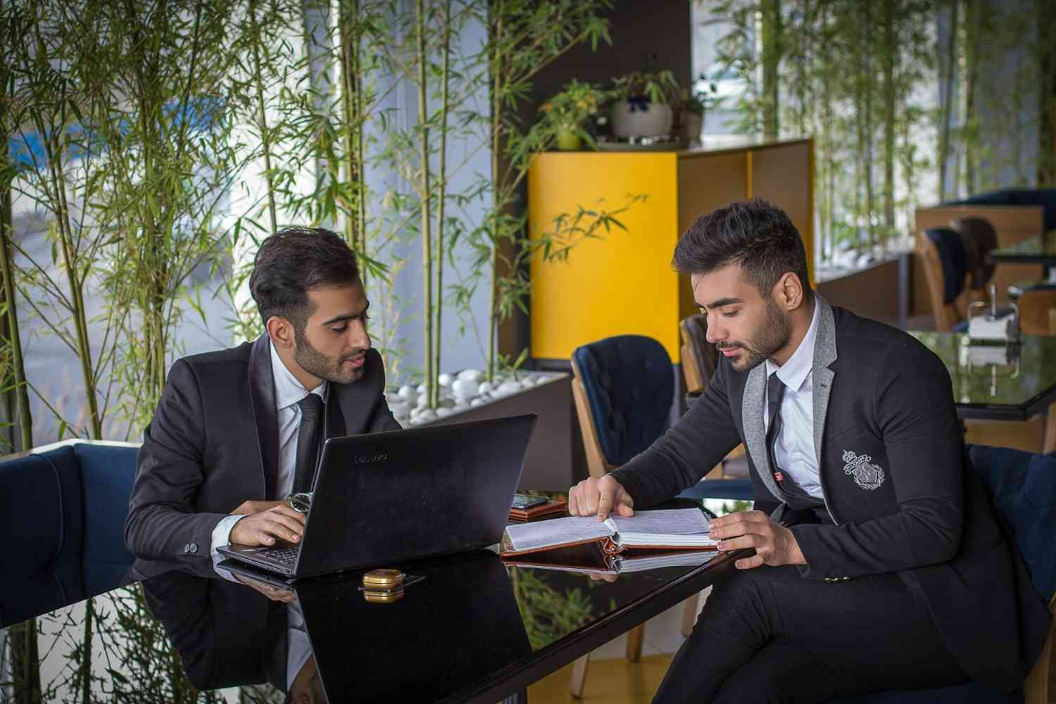 man in black suit jacket sitting beside man in black suit